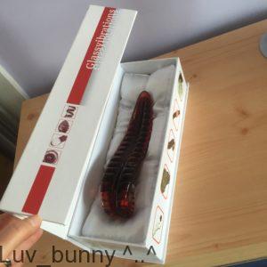 White flip-top box opened, with red glass Devils tongue textured dildo from Glassvibrations inside 