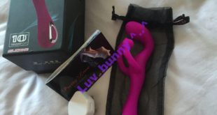 Purple silicone rechargeable G-spot vibrator with fluttery Clitoral stimulator. Displayed with packaging, instruction booklet and charging lead with mains adaptor