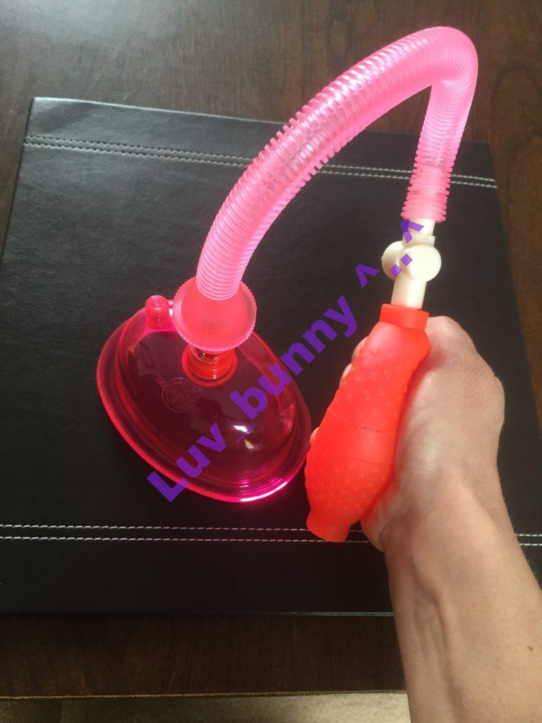 Doc Johnson Pussy pump pink plastic suction chamber, with pink hose attached.